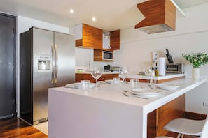 A modern kitchen with a built-in island, stainless steel appliances, and wooden cabinetry. - w* | Luxury & Cozy 1BR in Prime Polanco (Ciudad de México)
