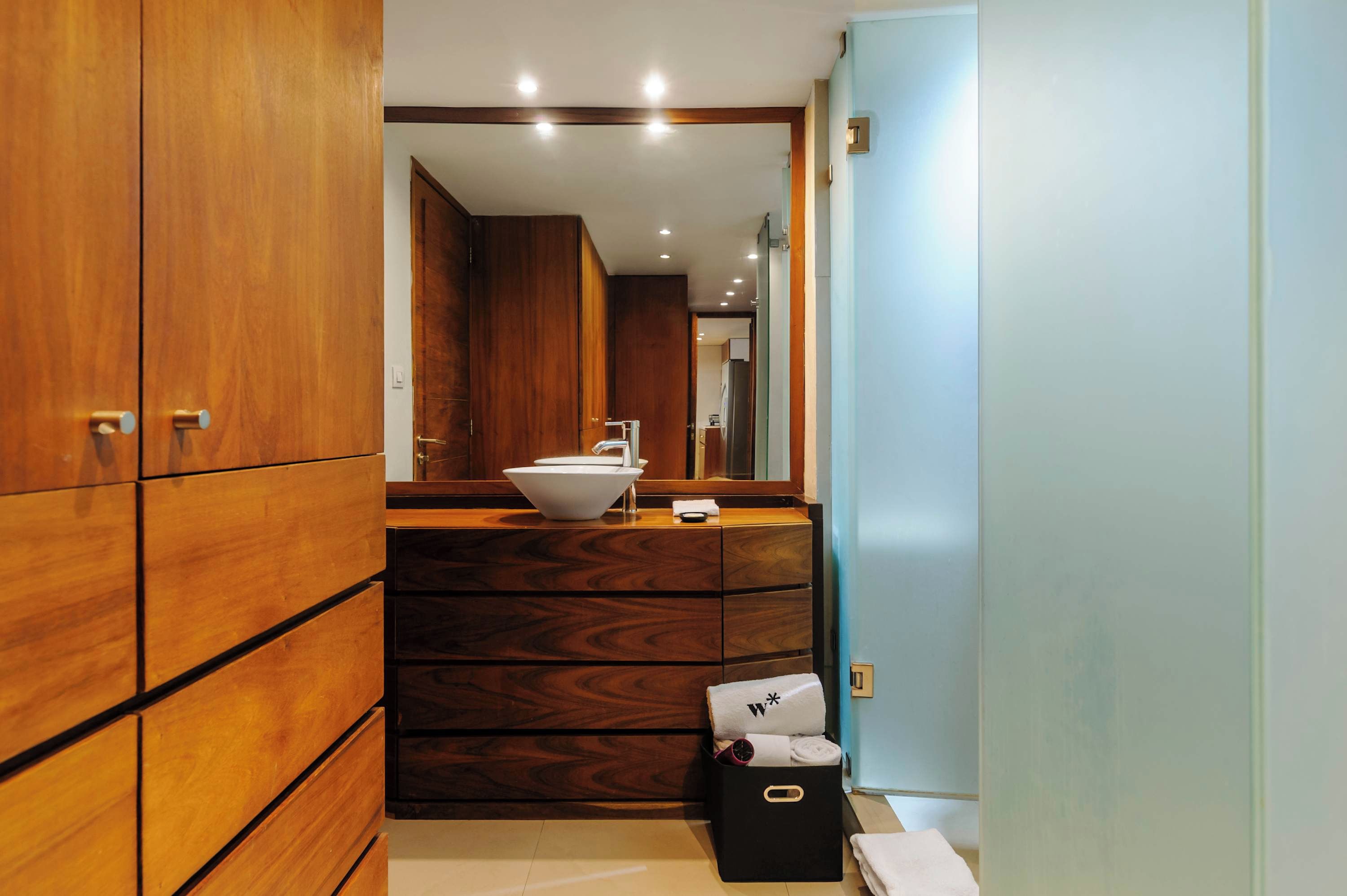 Une salle de bain moderne avec des meubles en bois, un lavabo blanc et une boîte de rangement noire.