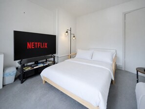A hotel room with a large bed, a television, a bedside table, and a floor lamp. - Family & Pet Friendly Flat | Free Parking&Wi-fi (Ceredigion)
