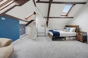A bedroom with a loft-style ceiling, a bed with a headboard, a nightstand, and a chair. - Family & Pet Friendly Flat | Free Parking&Wi-fi (Ceredigion)