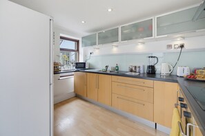 A modern kitchen with wooden cabinets, a microwave, a coffee maker, and a toaster. - Family & Pet Friendly Flat | Free Parking&Wi-fi (Ceredigion)