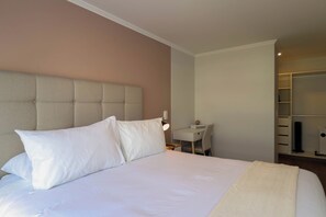 Una habitación de hotel con una cama grande, una mesita de noche, un escritorio y un armario.