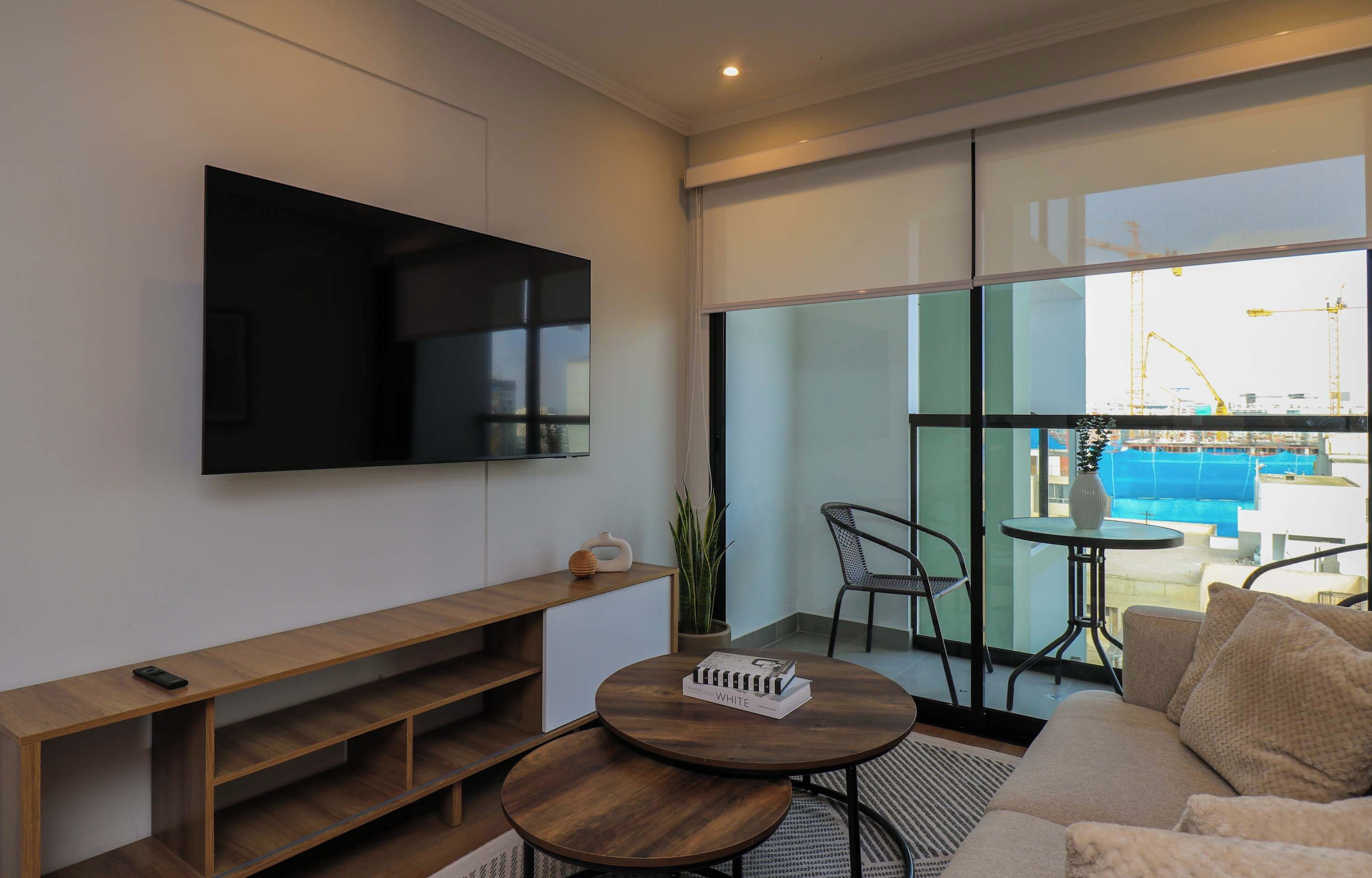 A modern living room with a flat-screen TV, a wooden bench, a round coffee table, and a sofa.