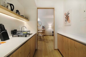 A modern kitchen with white countertops, wooden cabinets, and a built-in stove. - w | Upscale 2BR with Private Terrace in Roma Norte (Ciudad de México)