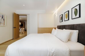 A hotel room with a large bed, a wooden headboard, and a dining area visible through an open door. - w | Upscale 2BR with Private Terrace in Roma Norte (Ciudad de México)