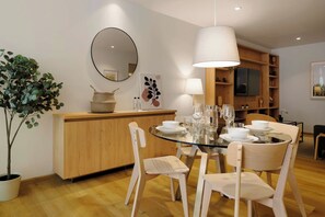 A modern dining area with a round glass table, white chairs, a wooden counter, and a hanging light fixture. - w | Upscale 2BR with Private Terrace in Roma Norte (Ciudad de México)