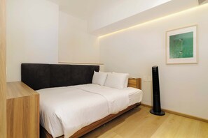 A bedroom with a bed, a bedside table, a lamp, a wall-mounted artwork, and a standing heater. - w | Upscale 2BR with Private Terrace in Roma Norte (Ciudad de México)