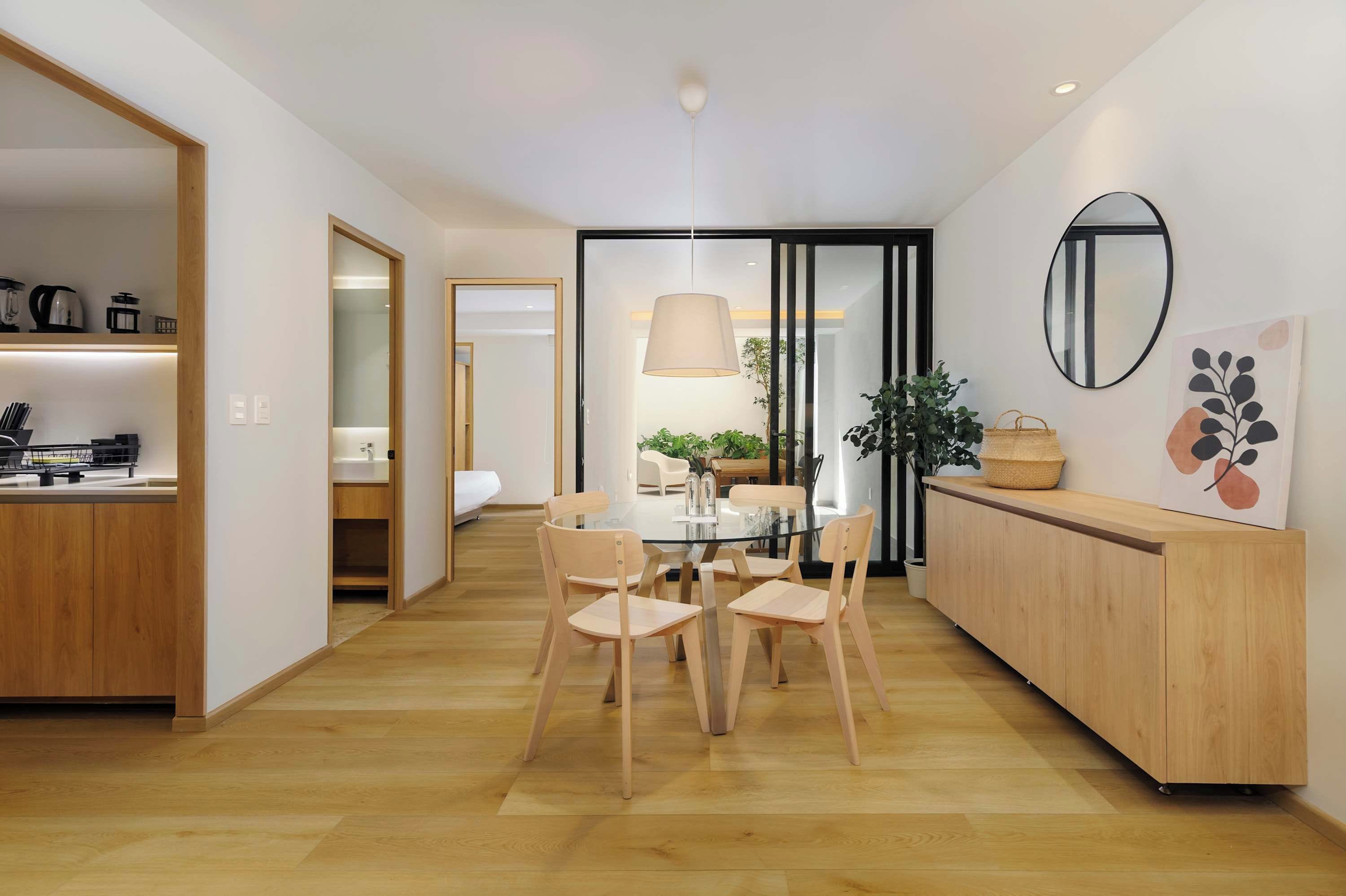 Eine moderne Küche mit Holzschränken, einem Esstisch mit Stühlen und einer hängenden Pendelleuchte.