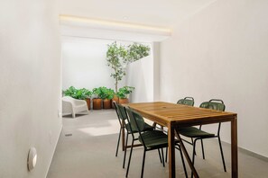 A modern dining area with a wooden table and chairs, potted plants, and a white chair. - w | Upscale 2BR with Private Terrace in Roma Norte (Ciudad de México)