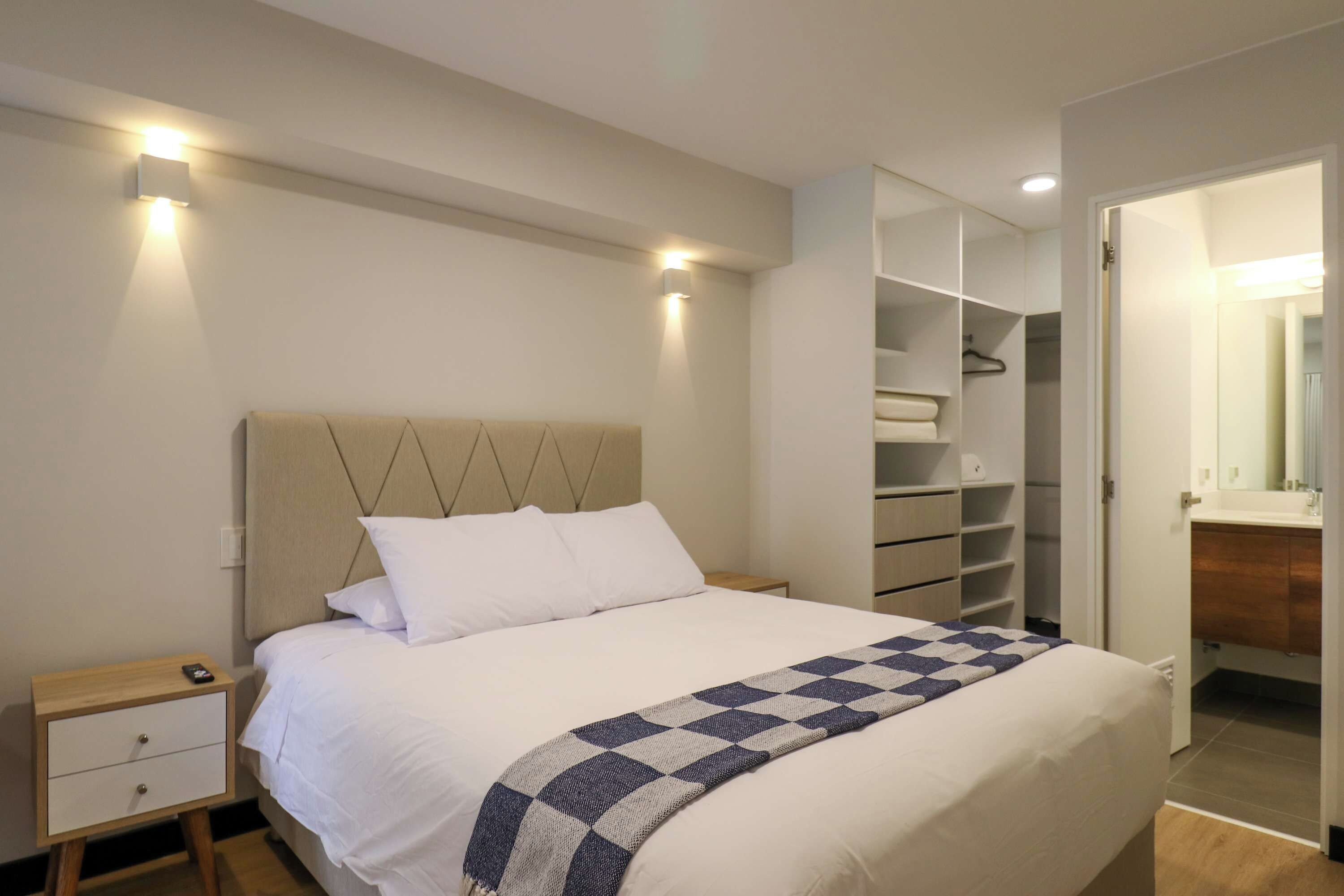Een slaapkamer met een bed, nachtkastjes, een kledingkast en een badkamer.