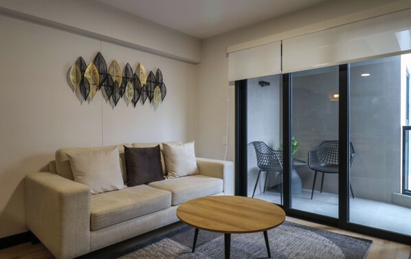 Een woonkamer met een bank, een salontafel en uitzicht door een glazen deur op een terras.