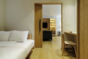 A hotel room with a bed, a desk, a chair, a TV, and a wall-mounted shelf with decorative items. - w* | Luxury 2BR with Private Terrace in Roma Norte (Ciudad de México)