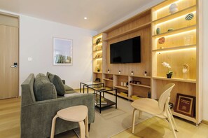 Ein modernes Wohnzimmer mit einer Couch, einem Couchtisch, einem Fernseher und Regalen mit Dekoration.