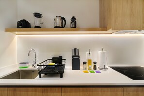 A modern kitchen with a white countertop, a black coffee machine, a kettle, a sink with a faucet, and a black dish rack. - w* | Luxury 2BR with Private Terrace in Roma Norte (Ciudad de México)