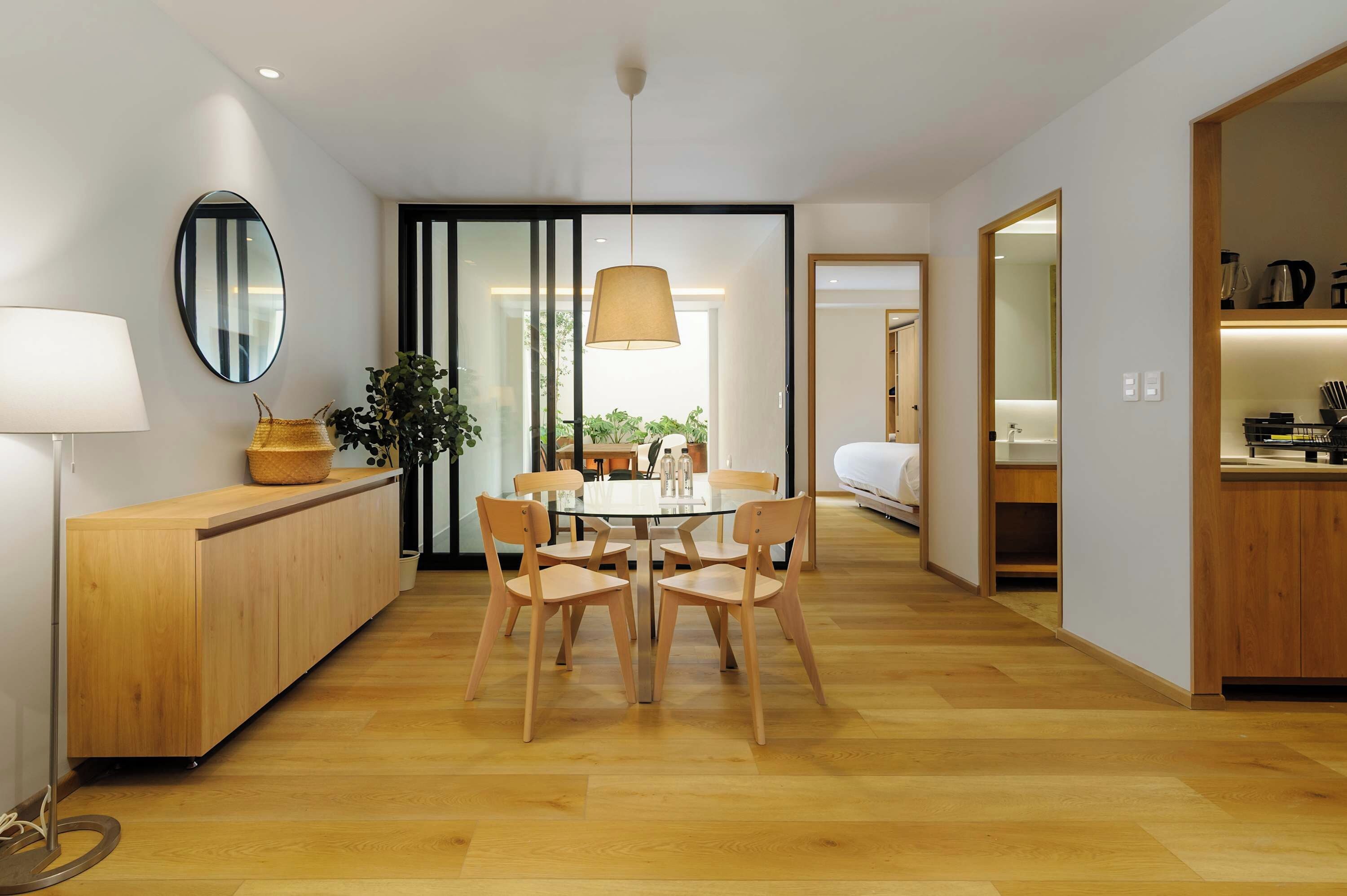 A modern kitchen with wooden cabinets, a dining table with chairs, and a large window.