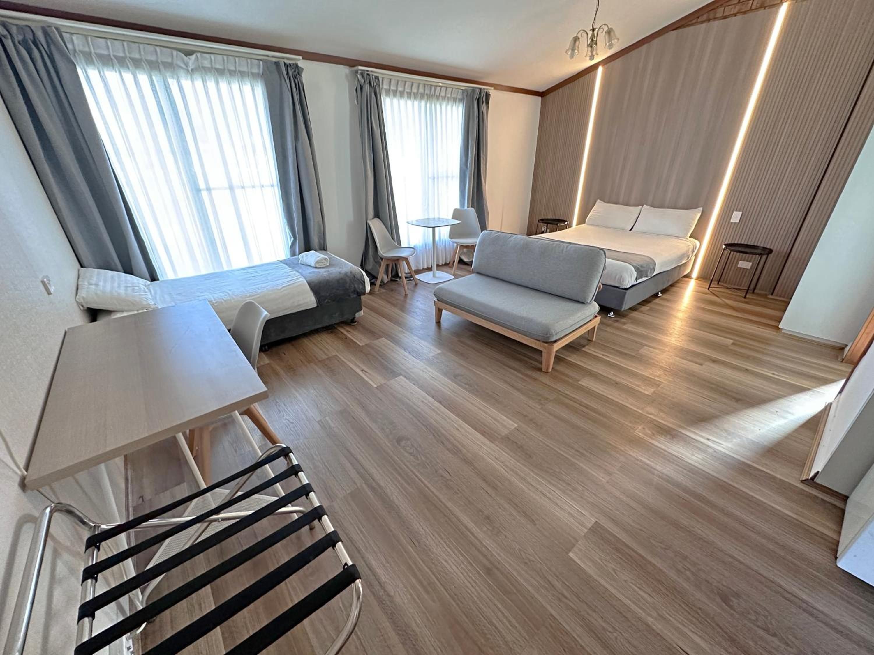 A modern hotel room with a bed, sofa, and a small table.