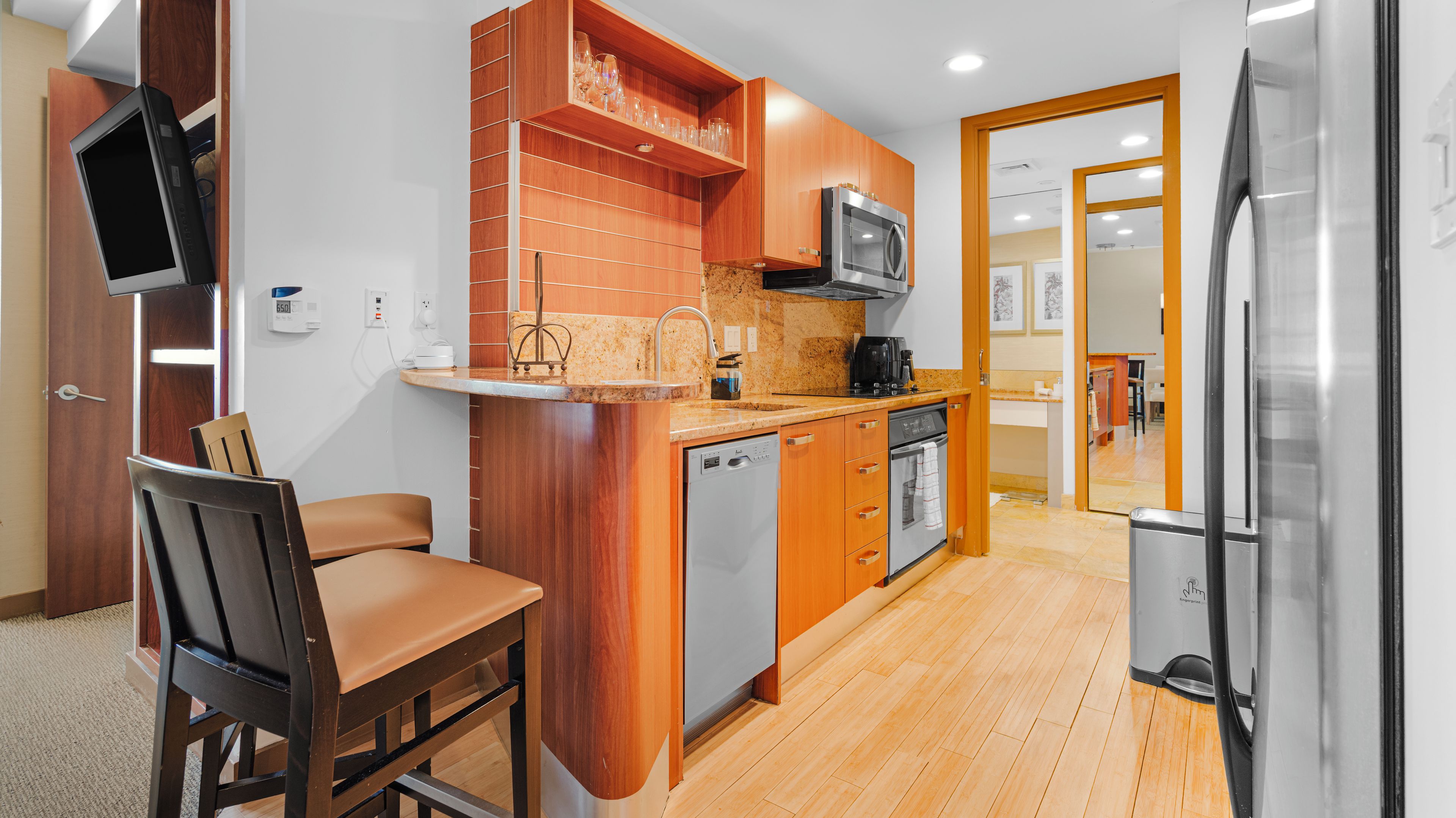 Une cuisine compacte dotée de meubles en bois, d’un four à micro-ondes encastré, d’un lave-vaisselle et d’un coin repas avec une chaise et une table.