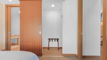 A hotel room with a bed, a wooden wardrobe, a small table, and a carpeted floor.