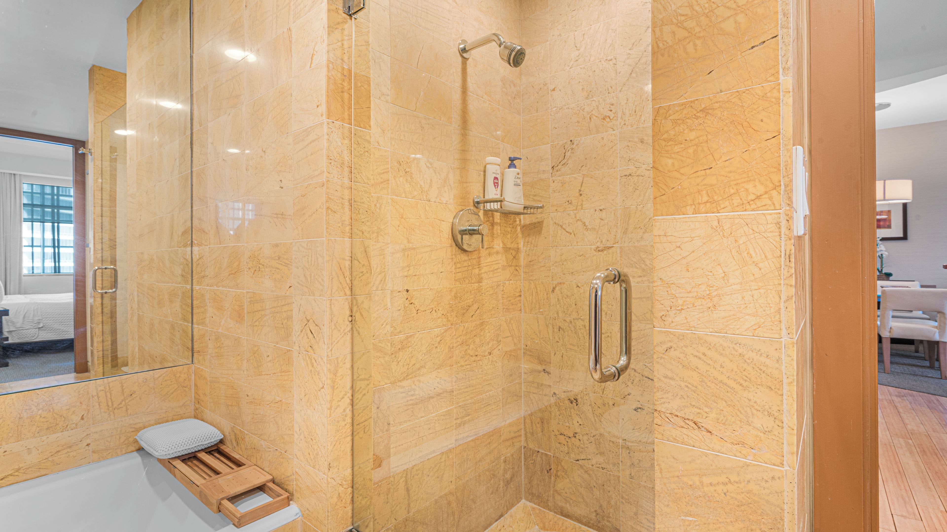 Ein modernes Badezimmer mit einer gläsernen Duschkabine, einer Holzbank und einer Handstange.