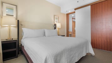 Ein Hotelzimmer mit einem Bett, zwei Nachttischlampen, einem Holzschrank und einem gerahmten Bild an der Wand.