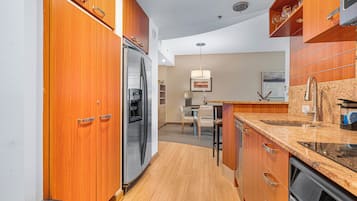 A modern kitchen with wooden cabinets, stainless steel appliances, a granite countertop, and a dining area with a table and chairs.
