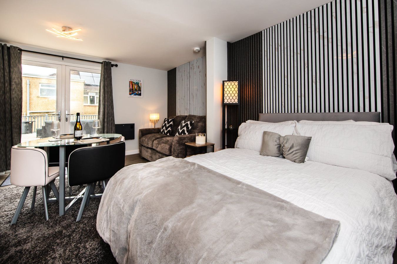 Een hotelkamer met een bed, een bureau, een stoel, een lamp en uitzicht.