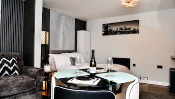 A modern hotel room with a bed, a dining table, and a sofa.