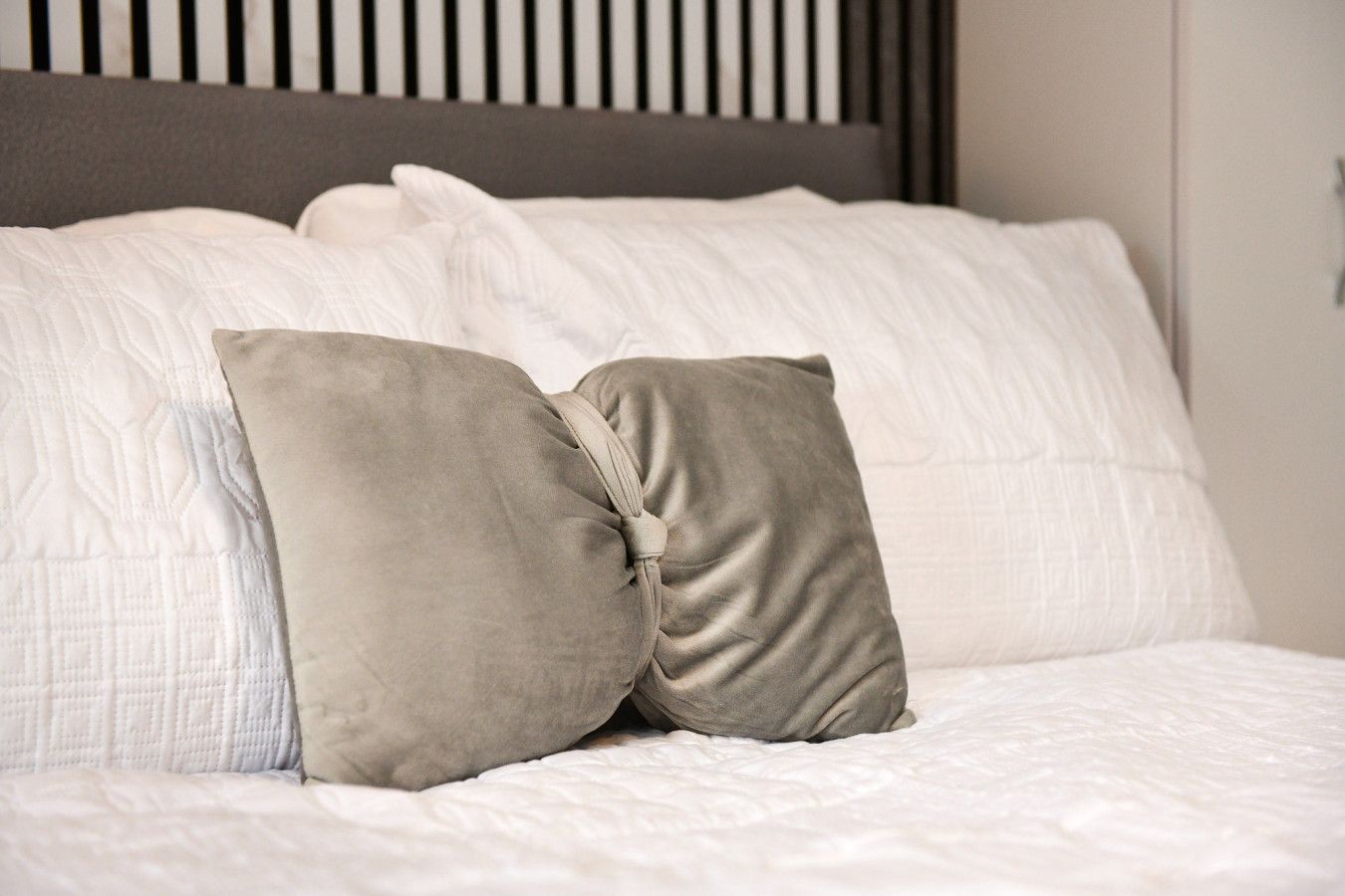 A bed with white bedding and two beige pillows.