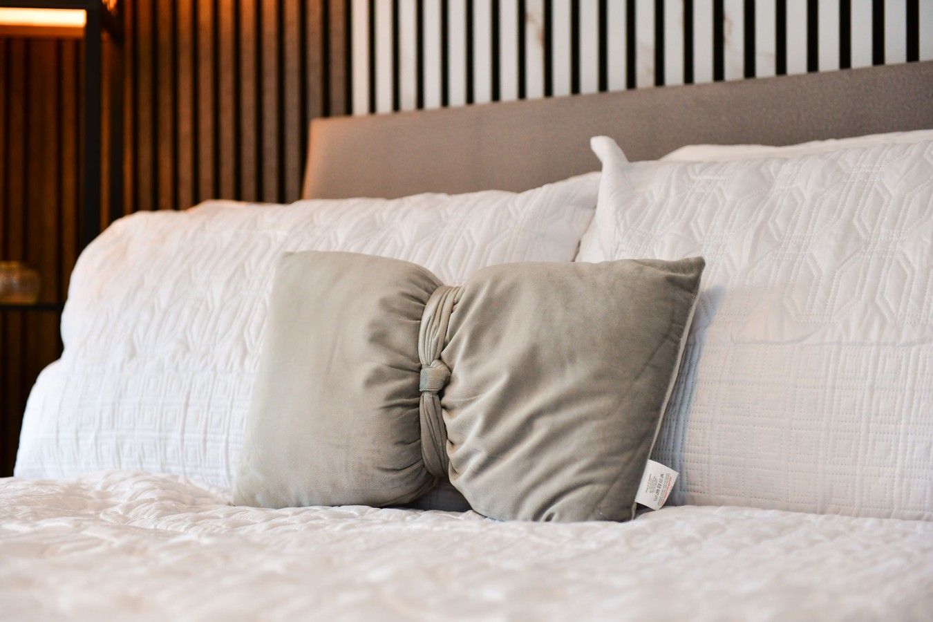 A bed with a grey headboard and two pillows.