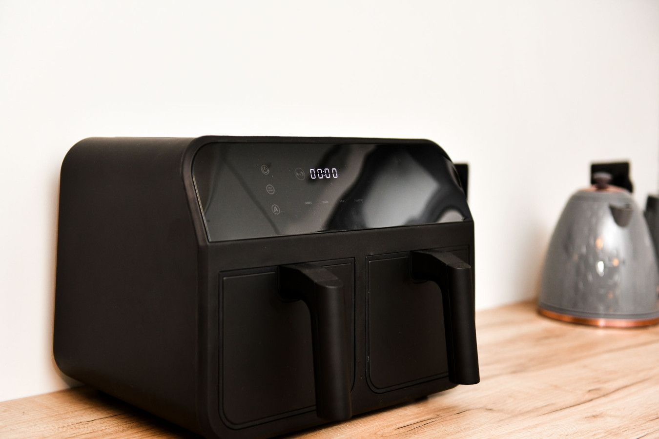A black coffee machine with a digital display on a wooden surface.