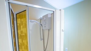 A glass-enclosed shower with a handheld showerhead and a wall-mounted control panel. - Homestead Lodge Motel (Timaru)