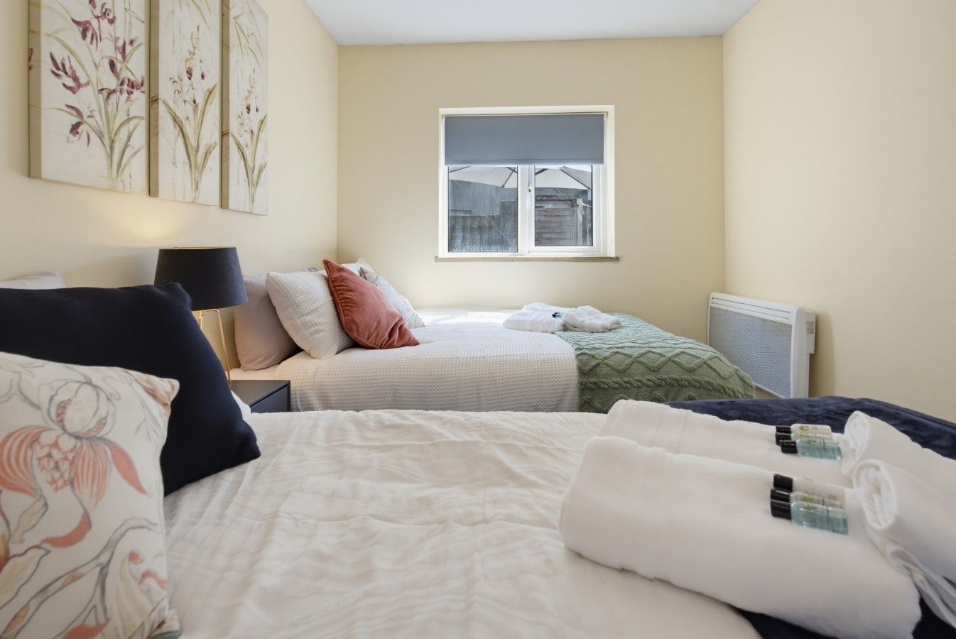 Ein Hotelzimmer mit Bett, Nachttisch, Lampe, Fenster und Heizkörper.