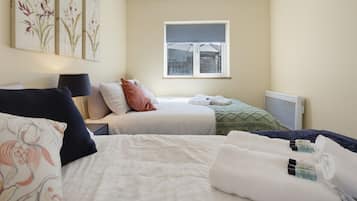 Ein Hotelzimmer mit Bett, Nachttisch, Lampe, Fenster und Heizkörper.