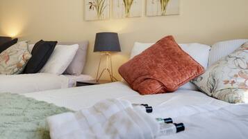 A hotel room with two beds, a bedside lamp, and floral artwork on the wall.