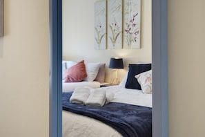 Ein Schlafzimmer mit einem Bett, Kissen, einer Nachttischlampe und Wandbildern.