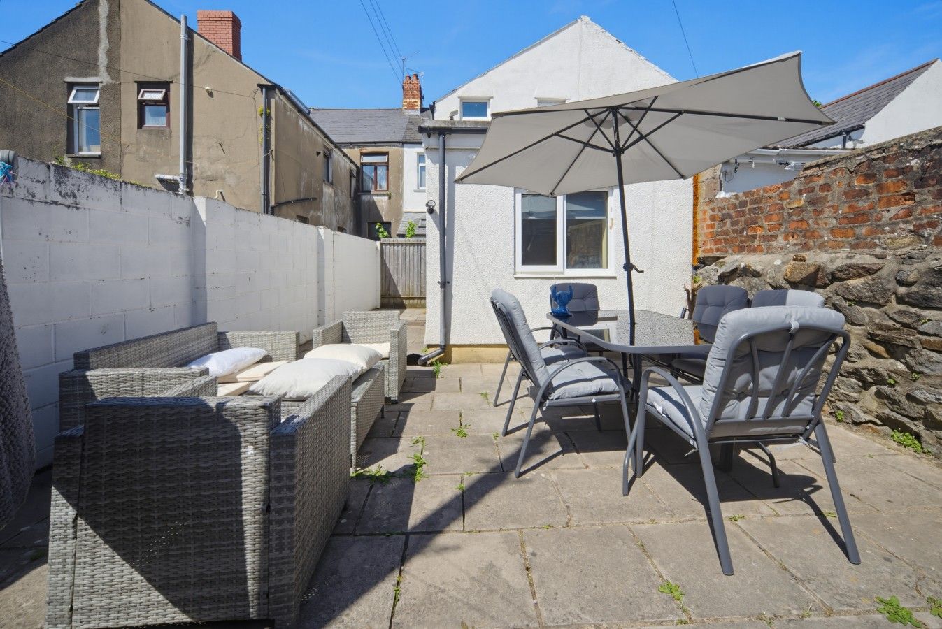 An outdoor patio with wicker furniture, a table, and an umbrella.