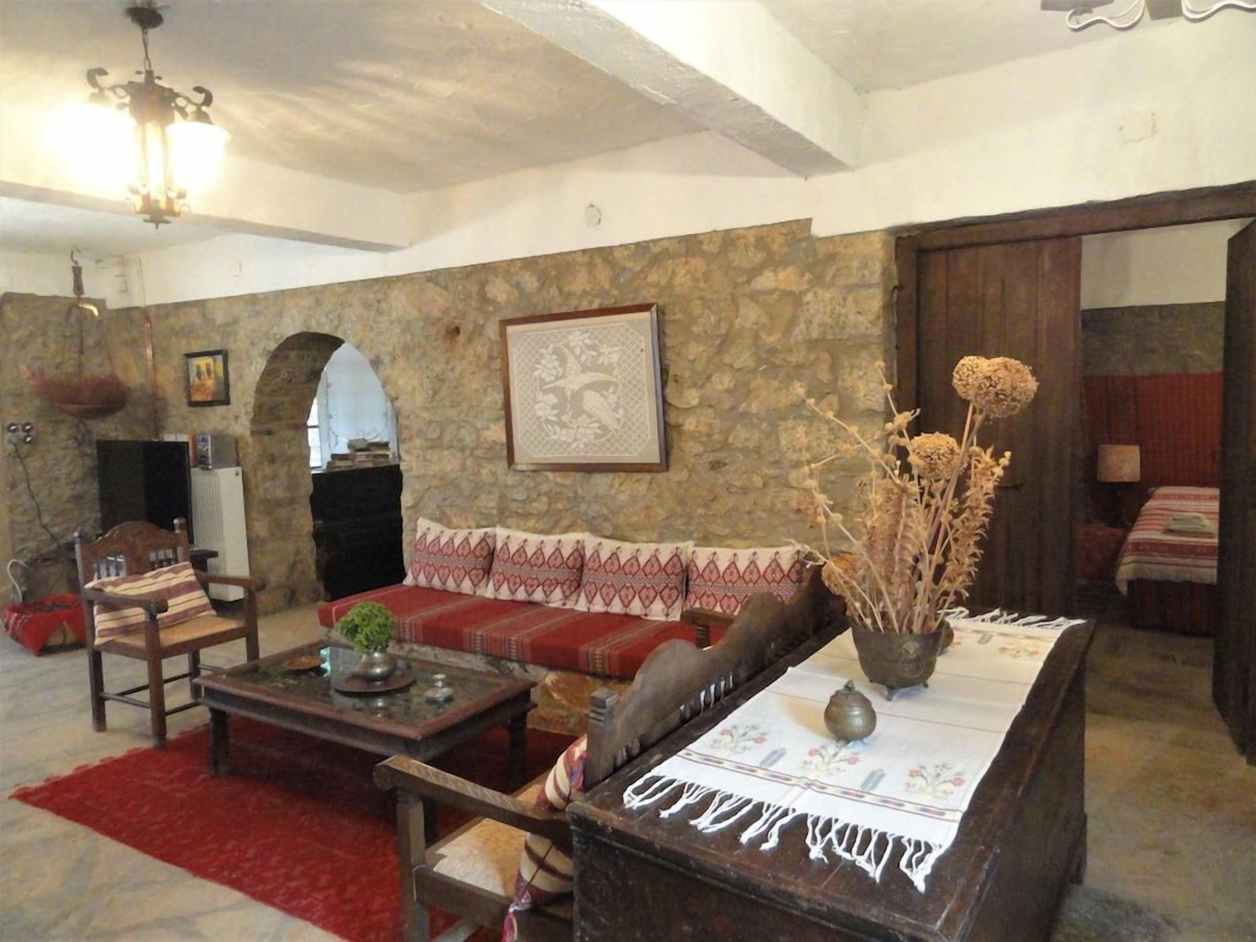 Ein gemütliches Wohnzimmer mit einer Steinwand, einem roten Sofa, einem Holztisch und einer Kristallleuchtre.