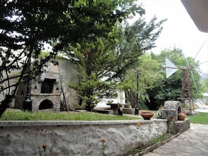 A stone wall with a small garden area, including a flower pot and a fountain. - Zeus House (Lasithi Plateau)