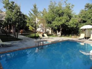 Piscina com espreguiçadeiras e área coberta.