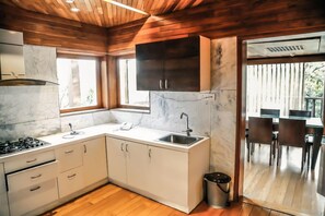 A modern kitchen with white cabinets, a marble backsplash, and a wooden ceiling. - Aamby Valley City, Lonavala (Paud)