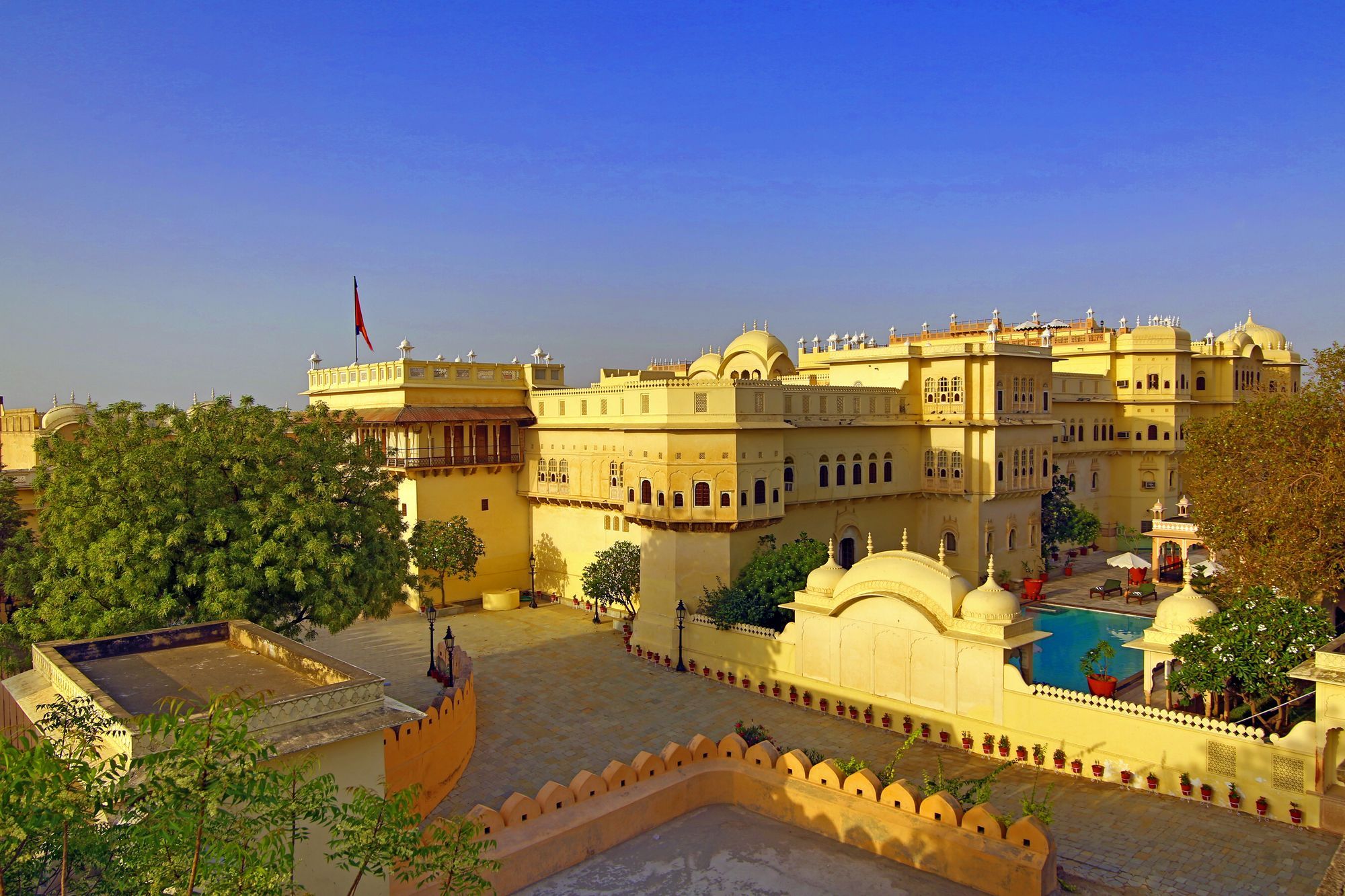 A large, historic building with multiple domes and a flag.