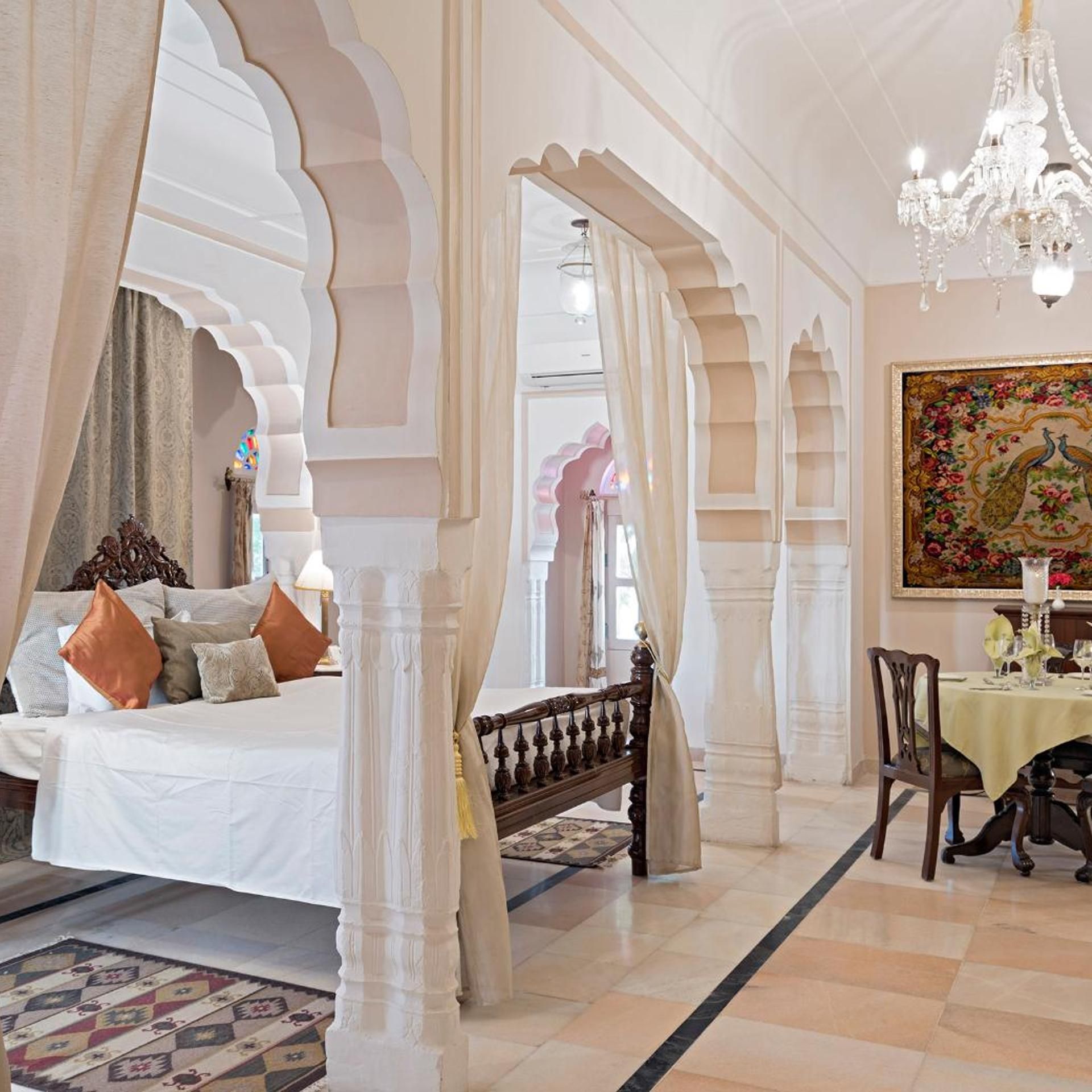 A room with a bed, a dining table, and a chandelier.