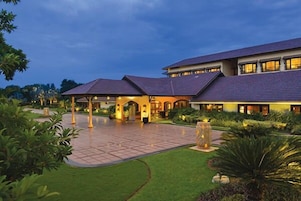 A hotel with a covered entrance, a well-maintained lawn, and a large water feature.