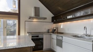 A modern kitchen with white cabinetry, stainless steel appliances, and a built-in oven. - Ginsetsu (Kutchan)