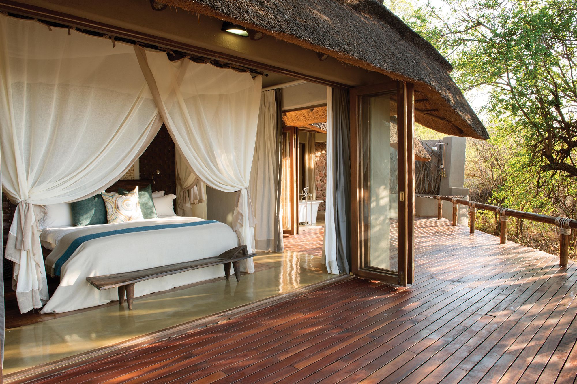 A bedroom with a bed, curtains, and a view of a bathroom.