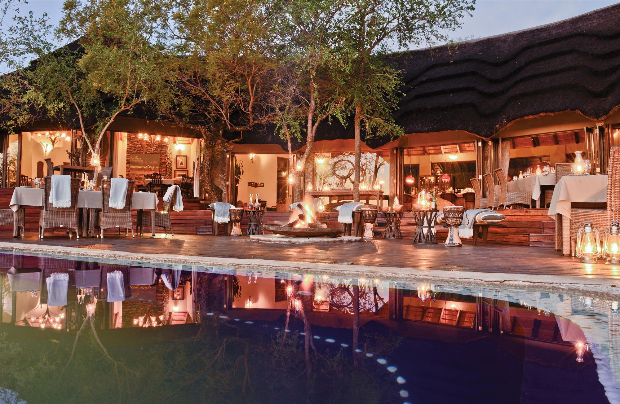 An outdoor dining area with tables and chairs, a pool, and a fire feature.