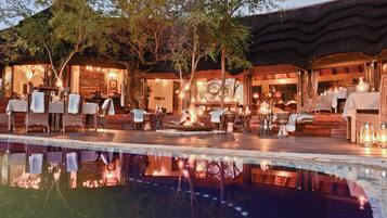 An outdoor dining area with tables and chairs, a pool, and a fire feature.