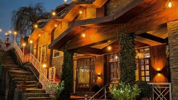 A multi-level wooden building with outdoor stairs and illuminated fixtures.