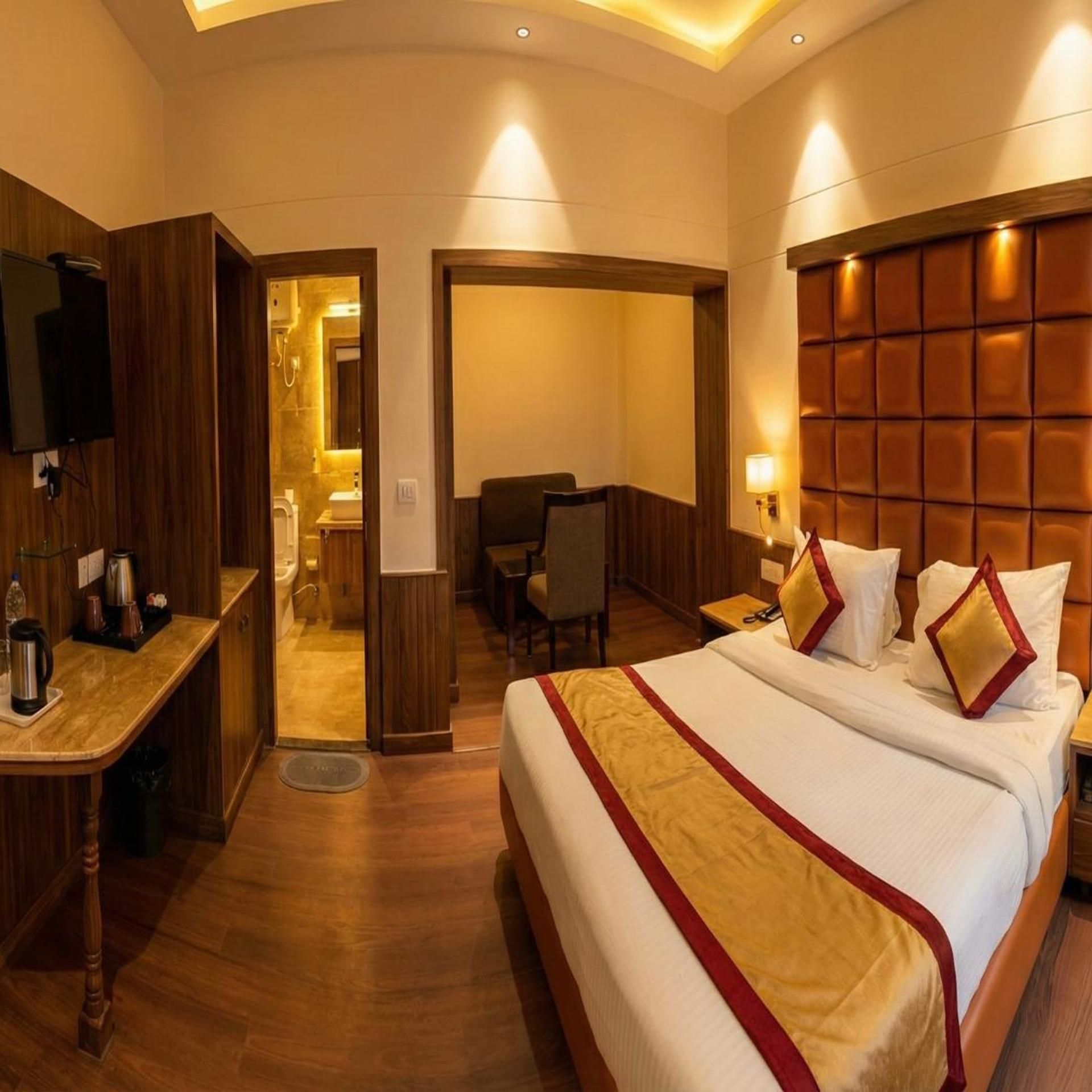 A hotel room with a large bed, a desk, a chair, and a television.
