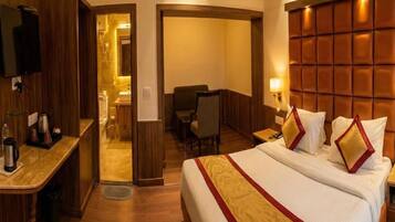 A hotel room with a large bed, a desk, a chair, and a television.